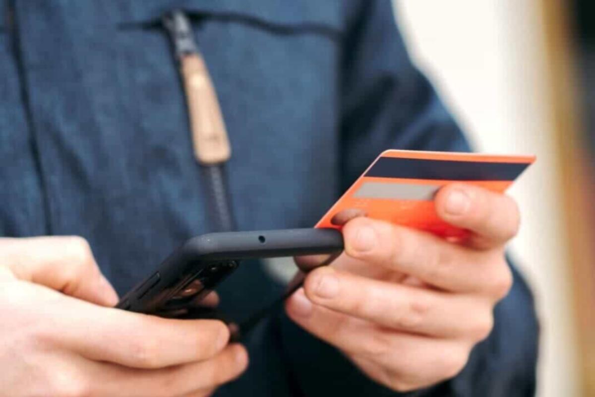 uomo con smartphone e carta di credito in mano