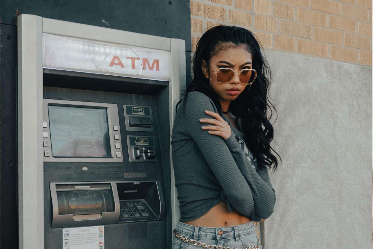 Una ragazza con gli occhiali da sole accanto a un ATM
