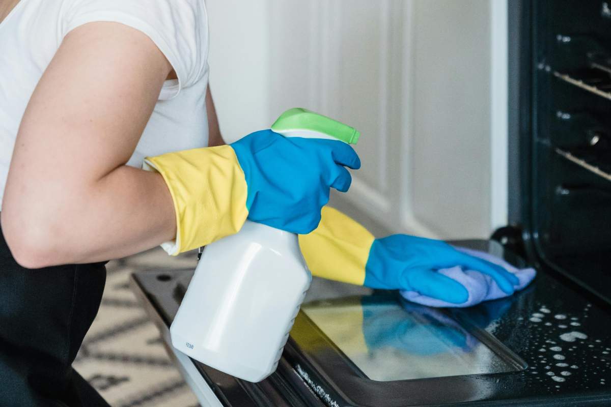 Donna che pulisce il forno con uno spray